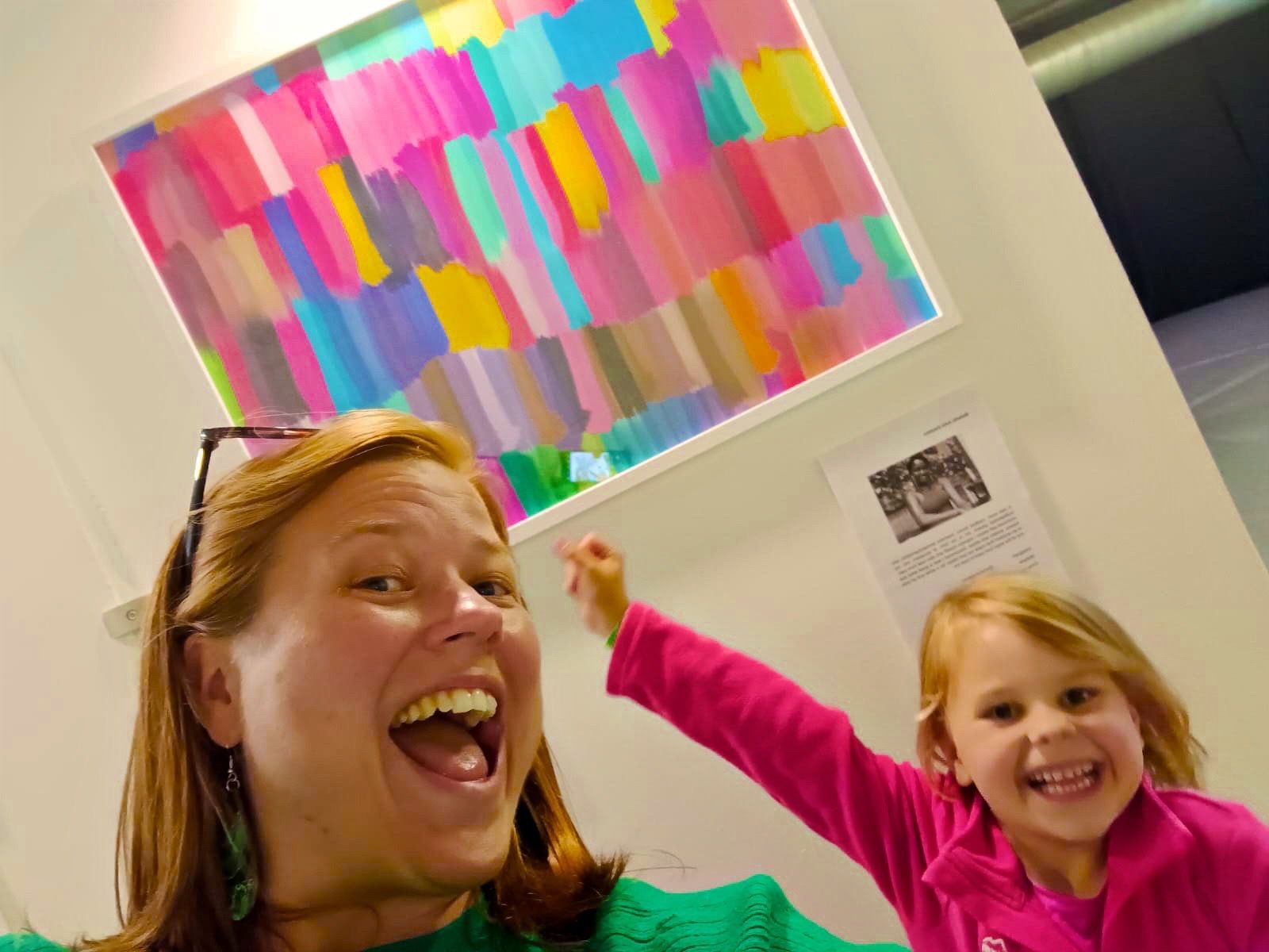 An adult and child smiling beneath A Colourful Pop at the exhibition